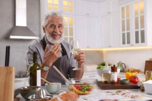 anziano davanti a cibo e bicchiere di vino