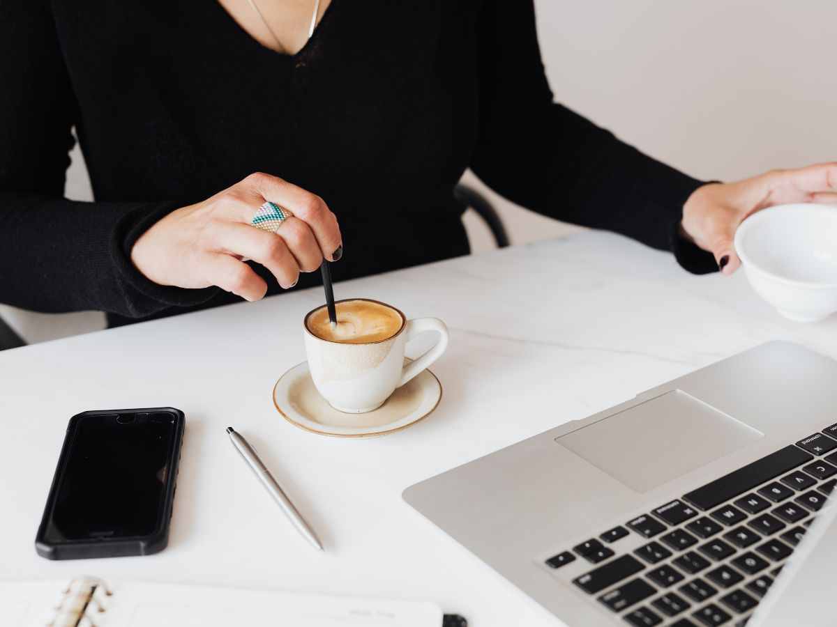 donna alla scrivania mescola caffè con un cucchiaino