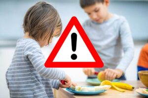 bambini mangiano frutta e segnale di pericolo
