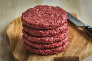 pila di hamburger sistemati su un tagliere