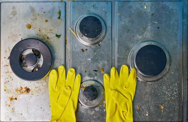 mani con guanti che puliscono cucina sporca